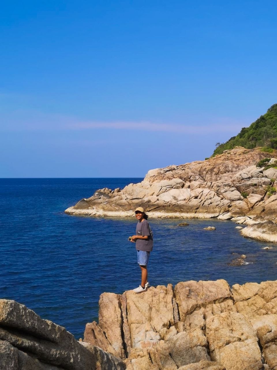 Joule Kasima, standing on coastal rocks overlooking the sea